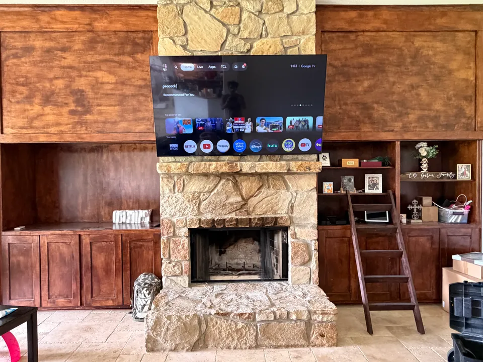 TV mounted above a stone fireplace between wooden cabinets.