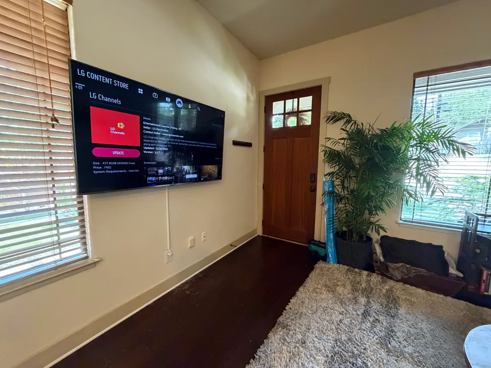 Wall-mounted TV with a white cord cover in a living room.