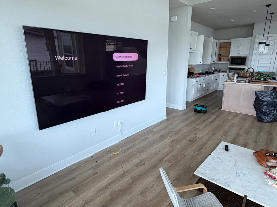 Large TV mounted on a wall beside an open kitchen.