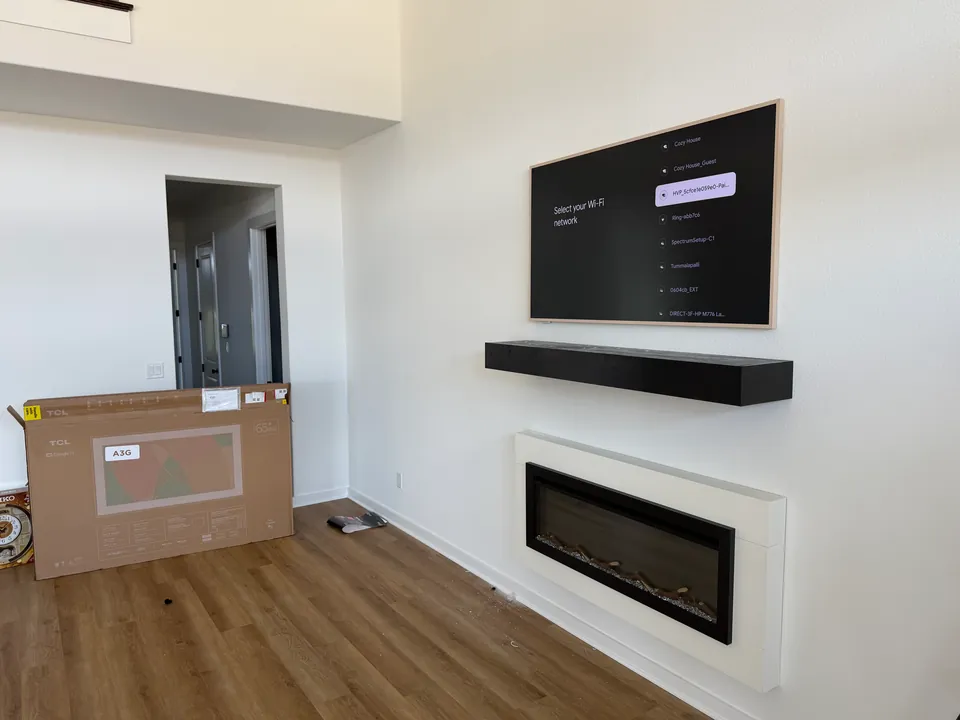 Framed TV mounted above a floating mantel and fireplace.