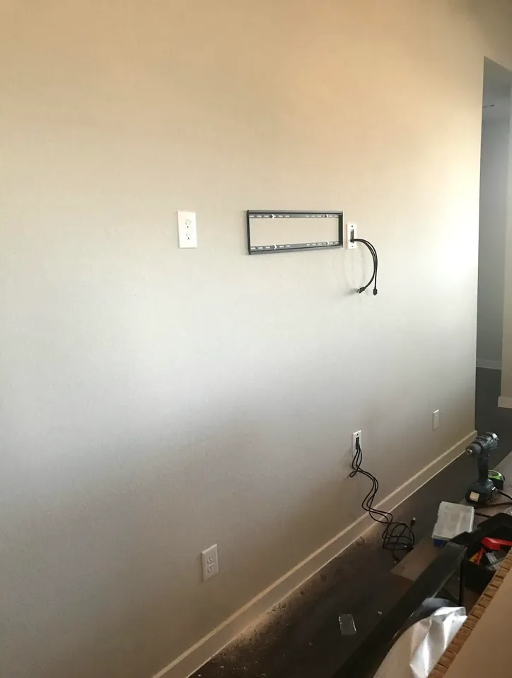 TV wall bracket with an outlet and separate cable openings.